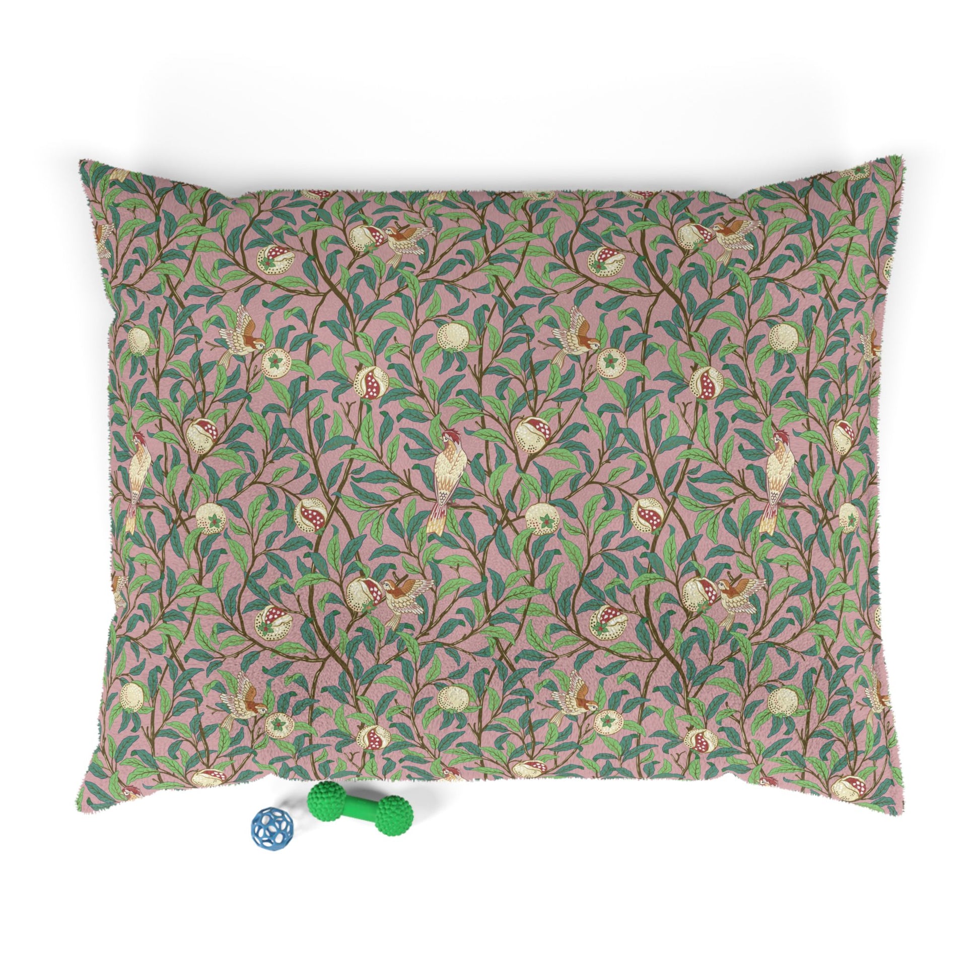 Decorative pillow with floral and bird pattern on a pink background, accompanied by two small toys.