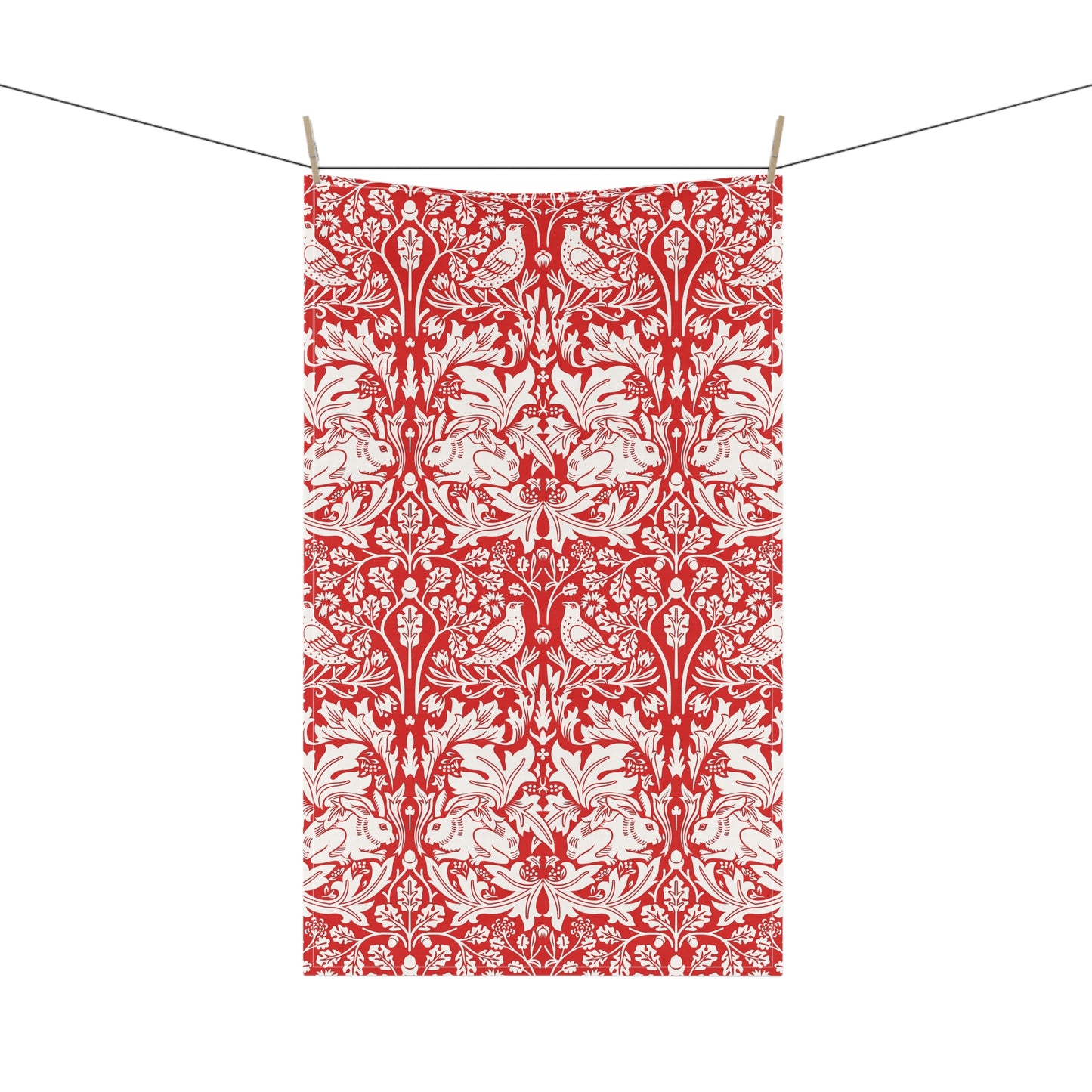 A rectangular tea towel with a red and white ornate floral damask pattern, hanging from a string with three wooden clothespins against a plain white background.