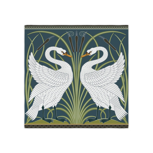 Square decorative table napkin featuring two white swans facing each other in an Art Nouveau style design on a dark teal background with green reeds and gold accents.