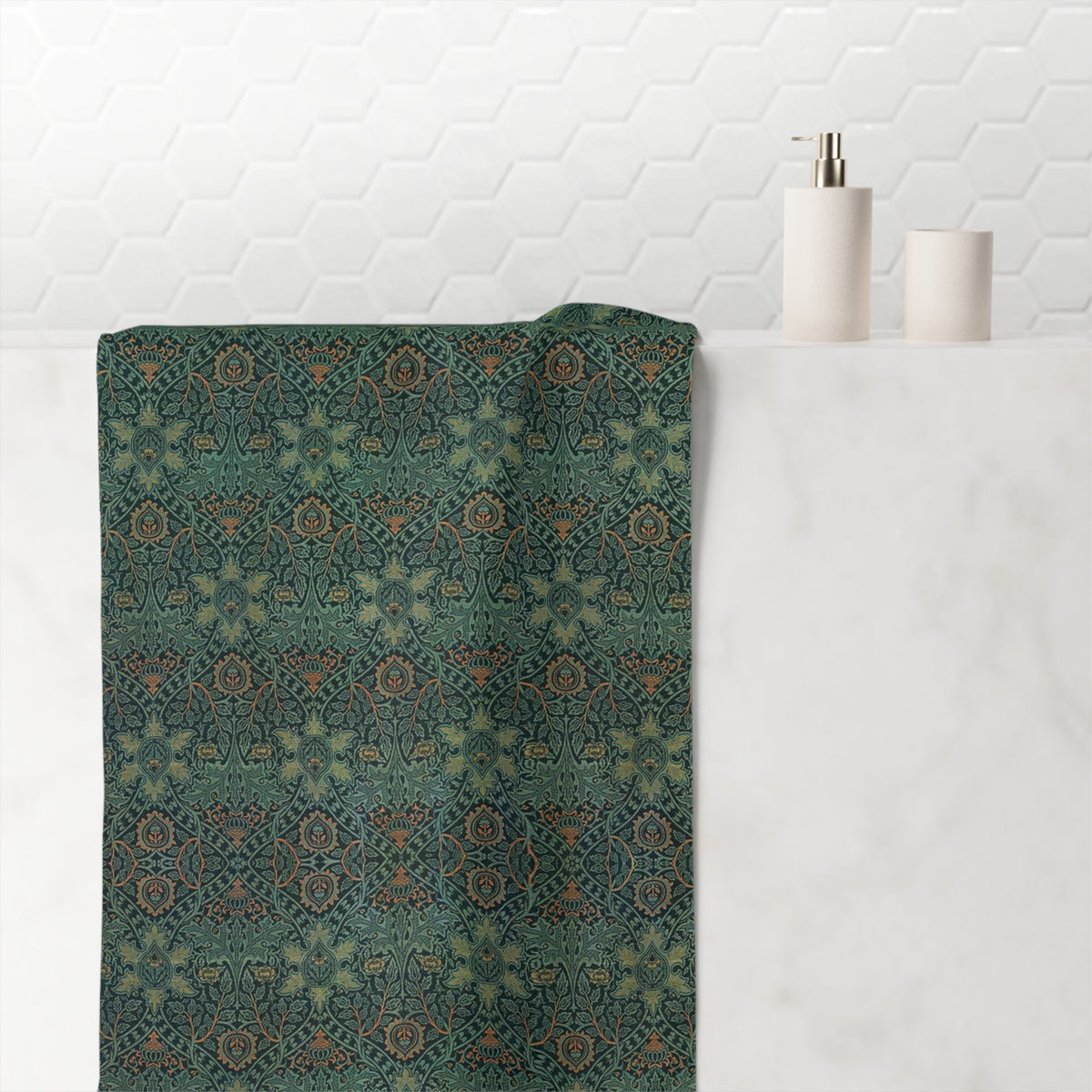 A rectangular bath towel with an intricate, repeating geometric and floral pattern in muted teal, olive green, rust orange, and beige tones, shown flat against a solid white background.
