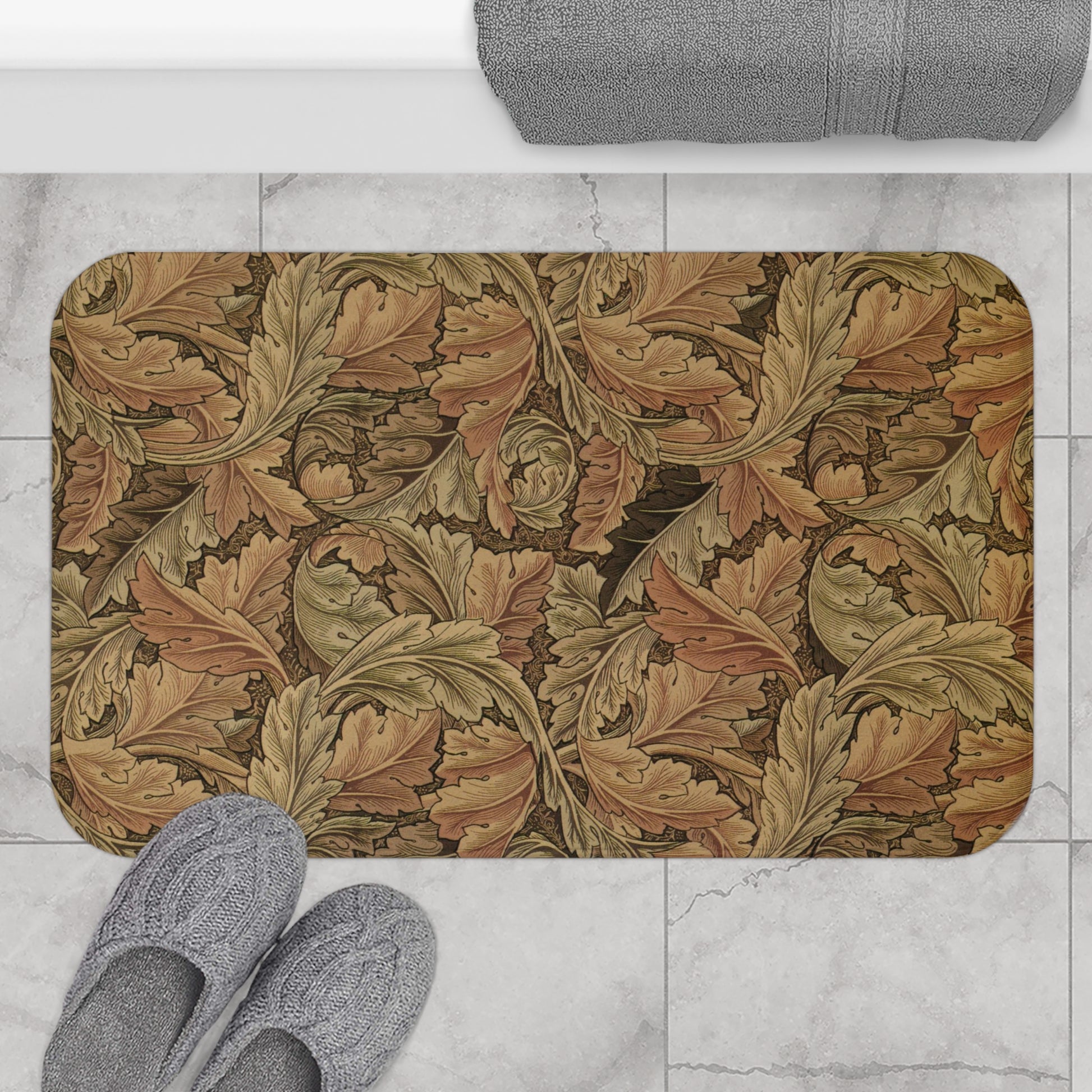 Decorative bath mat with leaf pattern on a marble floor with slippers and towel.