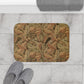Decorative doormat with leaf pattern on a marble floor with slippers and a towel.