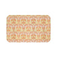 A rectangular microfibre bath mat with a floral pattern inspired by William Morris, in predominantly orange and yellow shades.