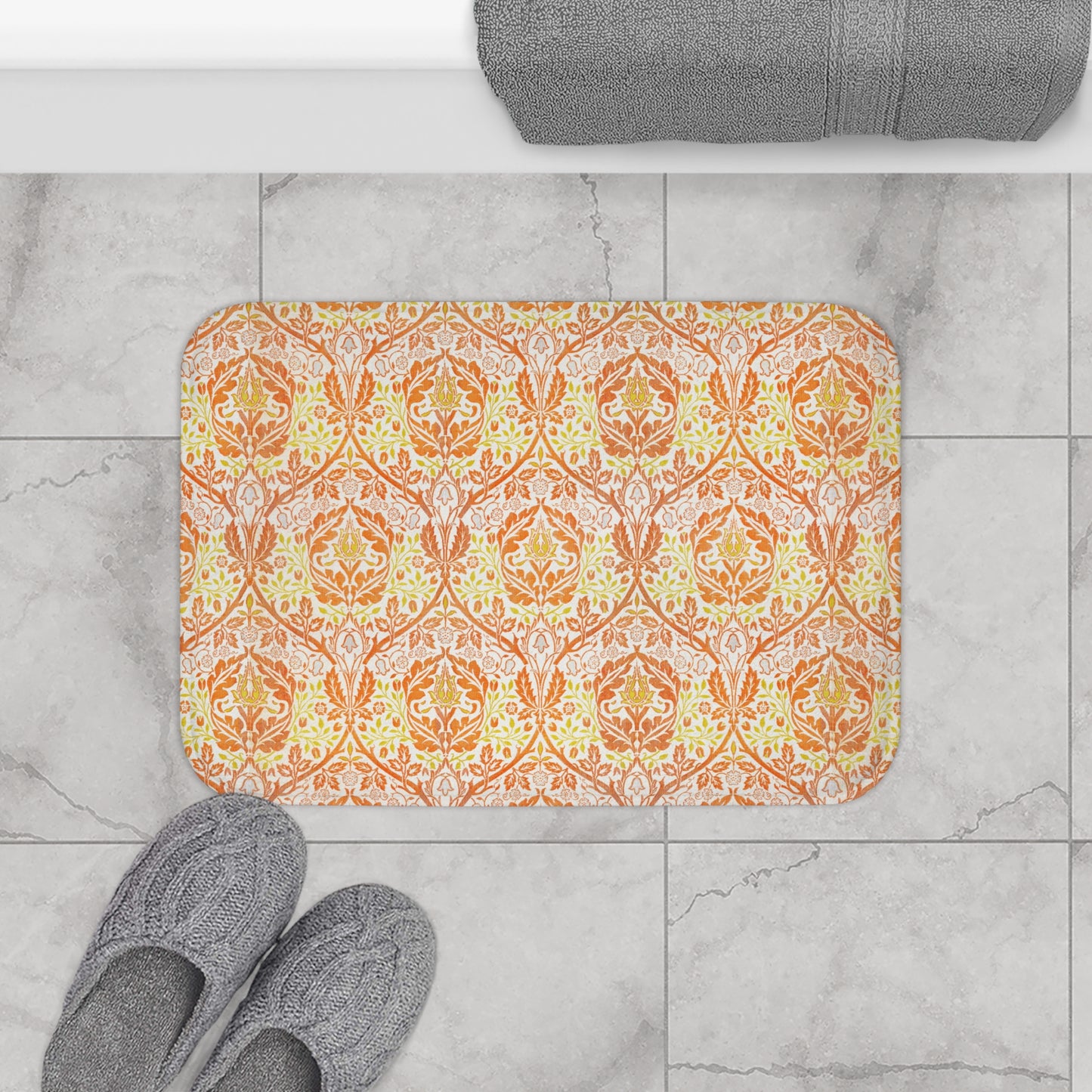 A rectangular microfibre bath mat with a floral pattern inspired by William Morris, in predominantly orange and yellow shades.