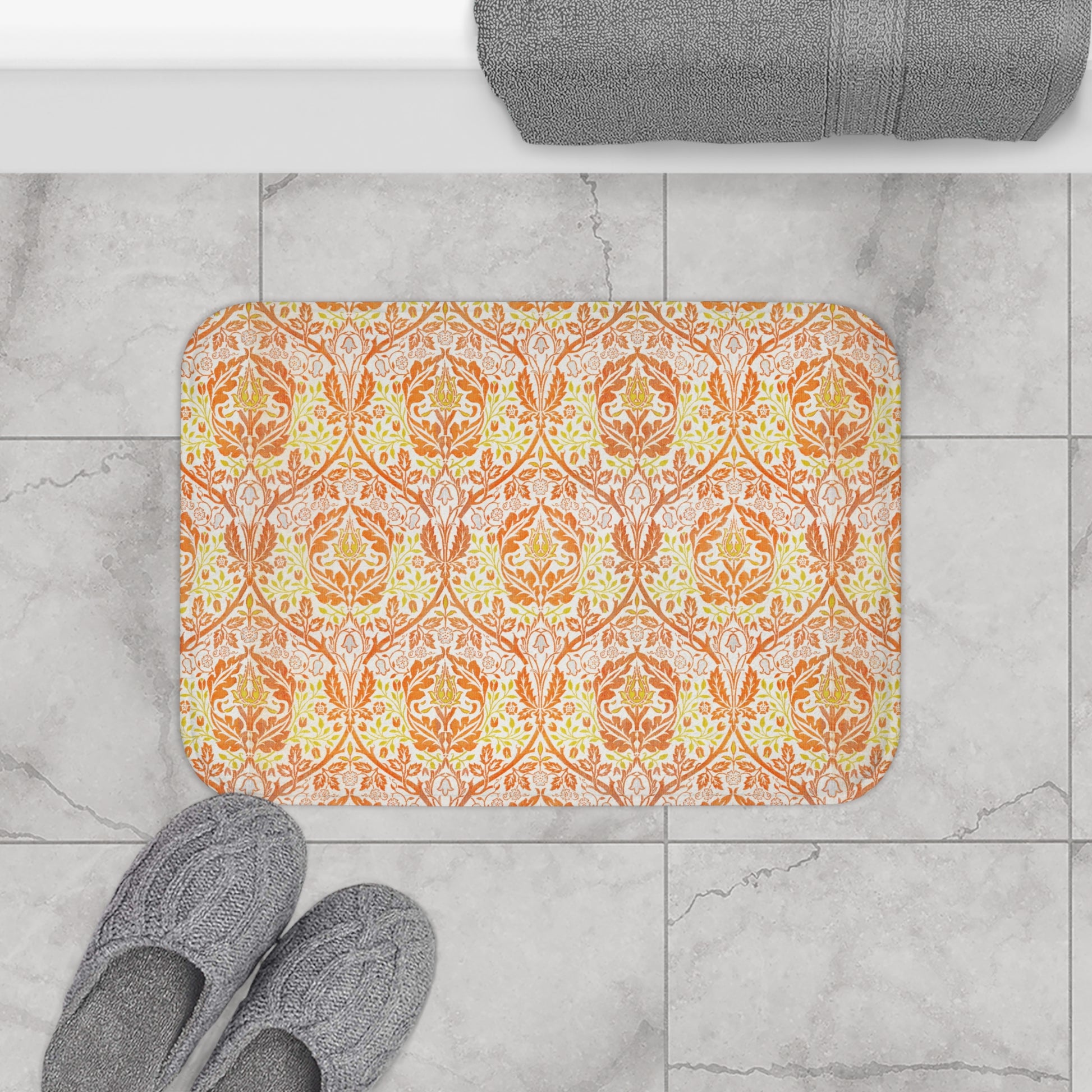 A rectangular microfibre bath mat with a floral pattern inspired by William Morris, in predominantly orange and yellow shades.