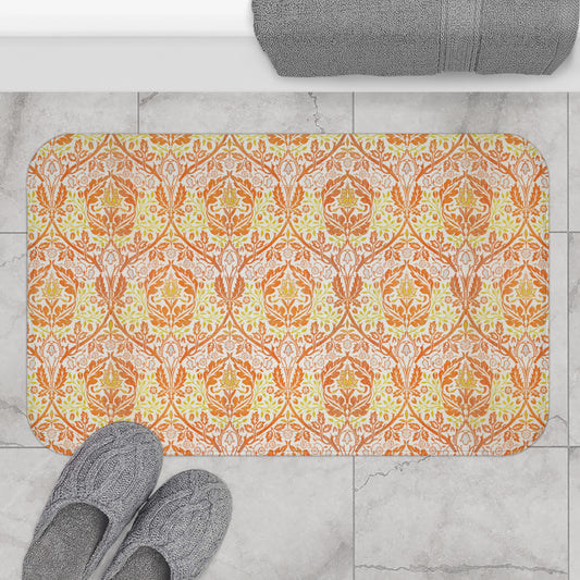 A rectangular microfibre bath mat with a floral pattern inspired by William Morris, in predominantly orange and yellow shades.
