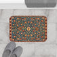 Decorative bath mat with floral pattern on a marble floor with slippers.