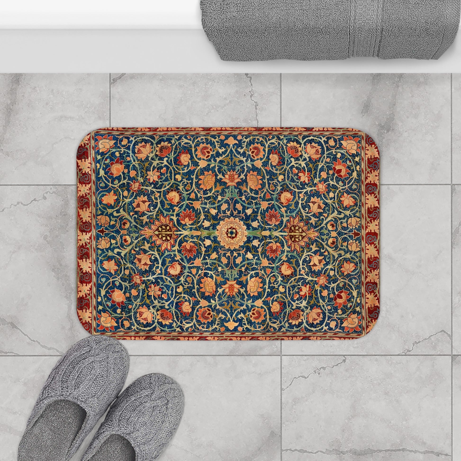 Decorative bath mat with floral pattern on a marble floor with slippers.