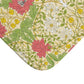 A rectangular microfibre bath mat with a floral pattern inspired by William Morris, in colours green, pink, yellow, and white.