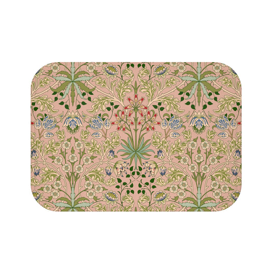 A rectangular microfibre bath mat with a floral pattern inspired by William Morris, in colors pink, green, and white.