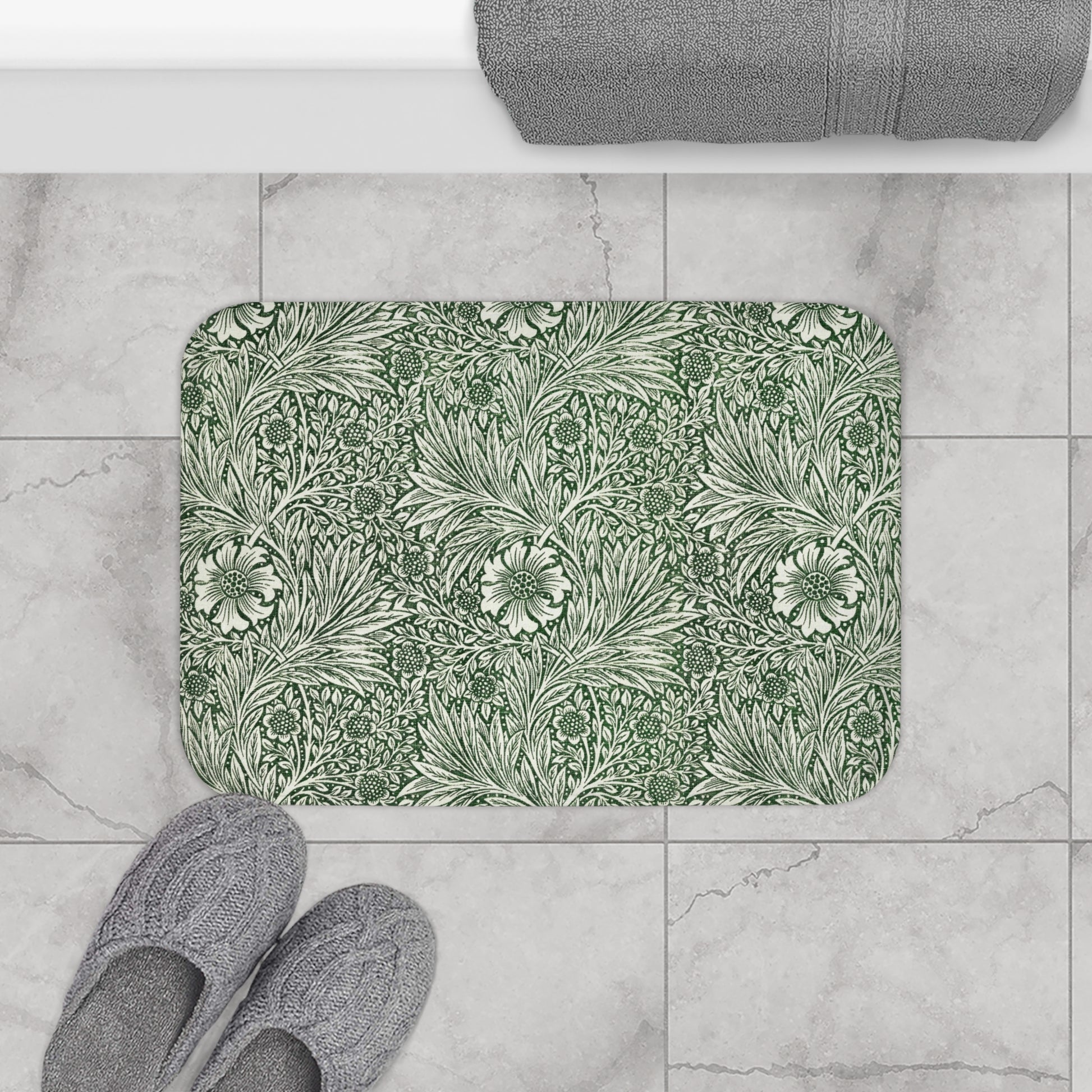 A rectangular microfibre bath mat with an all-over print of green and white floral patterns inspired by William Morris.