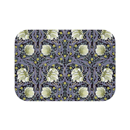A rectangular microfibre bath mat with a floral pattern in shades of purple and green, inspired by William Morris' design.