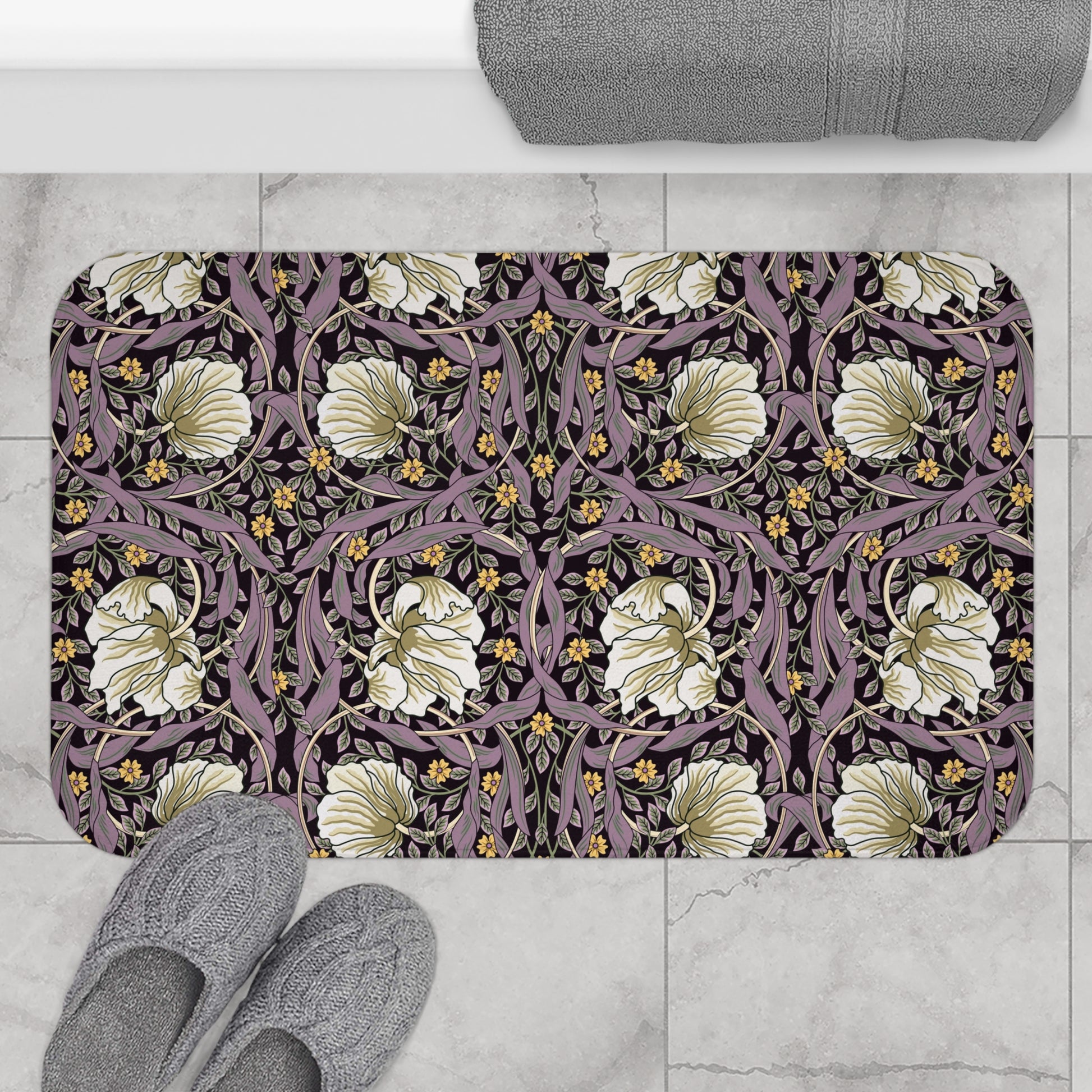 A rectangular microfibre bath mat with a floral pattern inspired by William Morris, predominantly in pink, purple and gold colours.