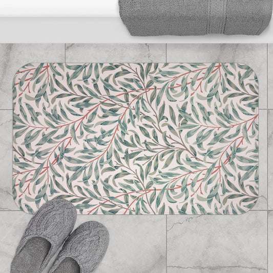 Floral-patterned bath mat on a tiled floor with slippers and a towel.