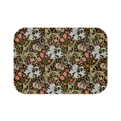 A rectangular microfibre bath mat with a floral pattern inspired by William Morris, predominantly in dark colours with a mix of lilies and other foliage.