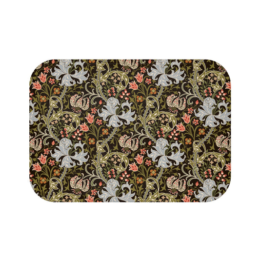 A rectangular microfibre bath mat with a floral pattern inspired by William Morris, predominantly in dark colours with a mix of lilies and other foliage.