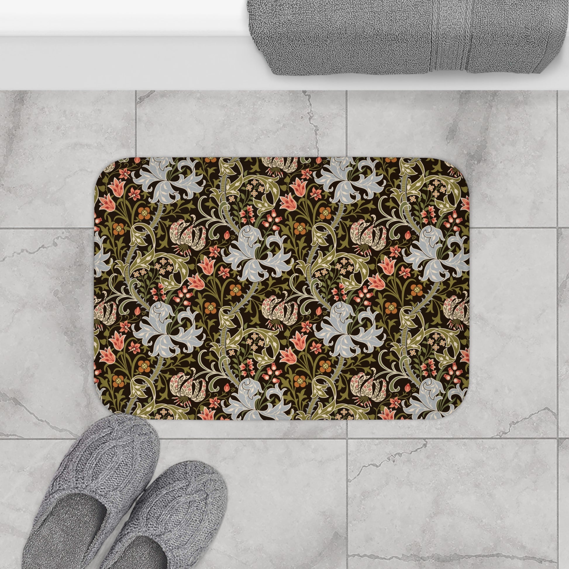 A rectangular microfibre bath mat with a floral pattern inspired by William Morris, predominantly in dark colours with a mix of lilies and other foliage.