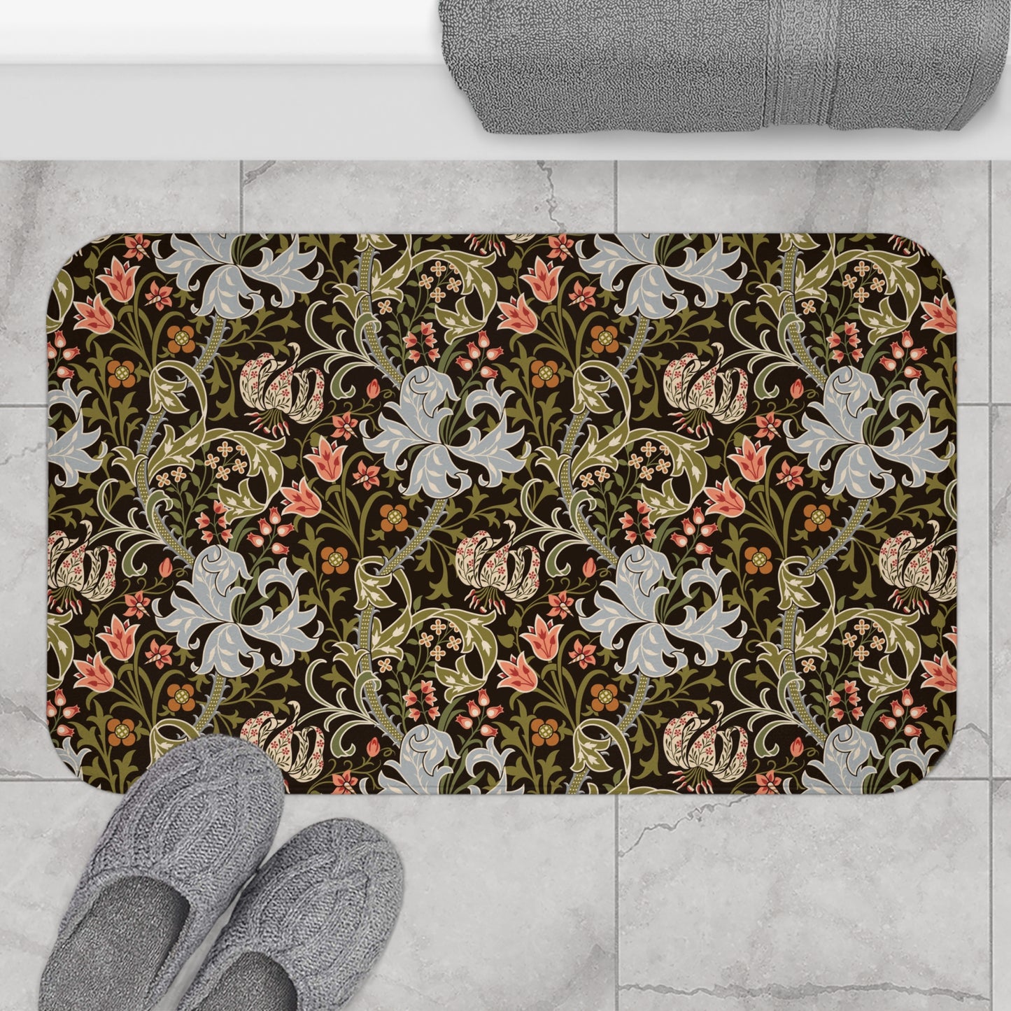 A rectangular microfibre bath mat with a floral pattern inspired by William Morris, predominantly in dark colours with a mix of lilies and other foliage.