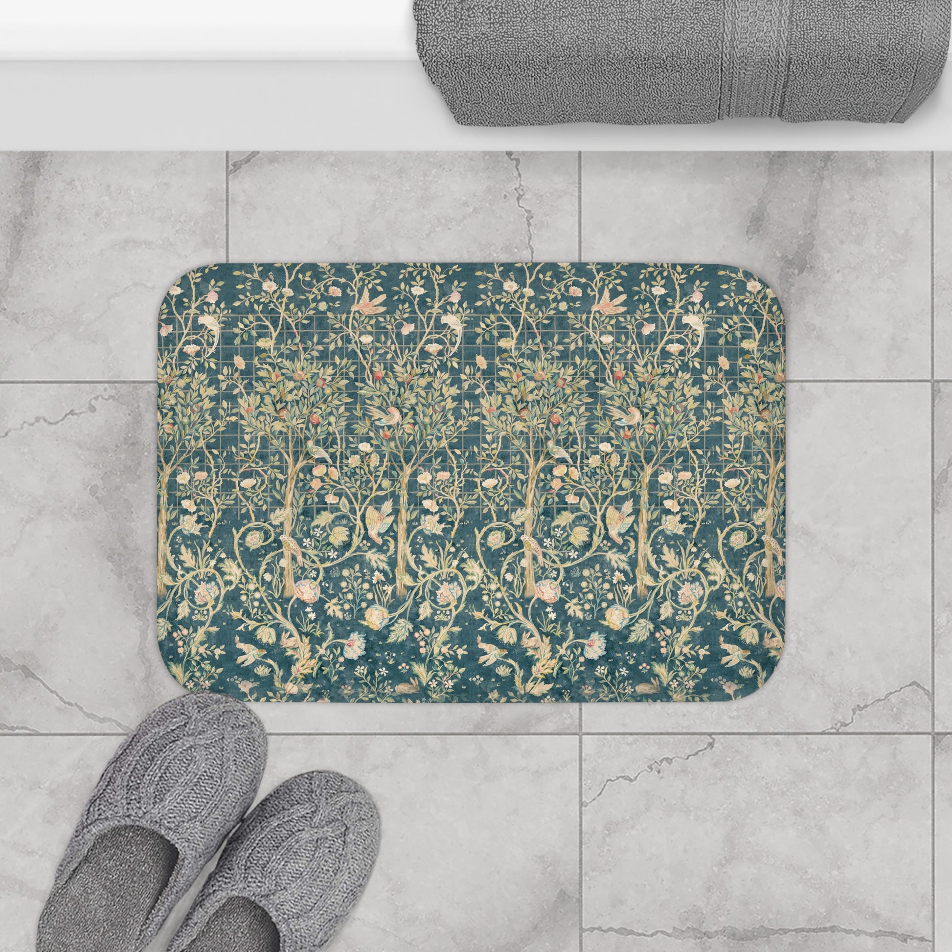 Decorative doormat with floral pattern on a tiled floor, next to slippers and a bath mat.