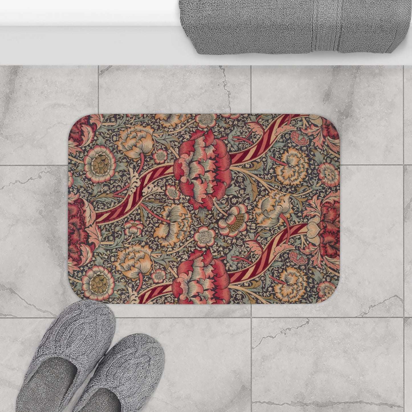 A rectangular microfibre bath mat with a floral pattern inspired by William Morris, predominantly red with a non-slip black border.