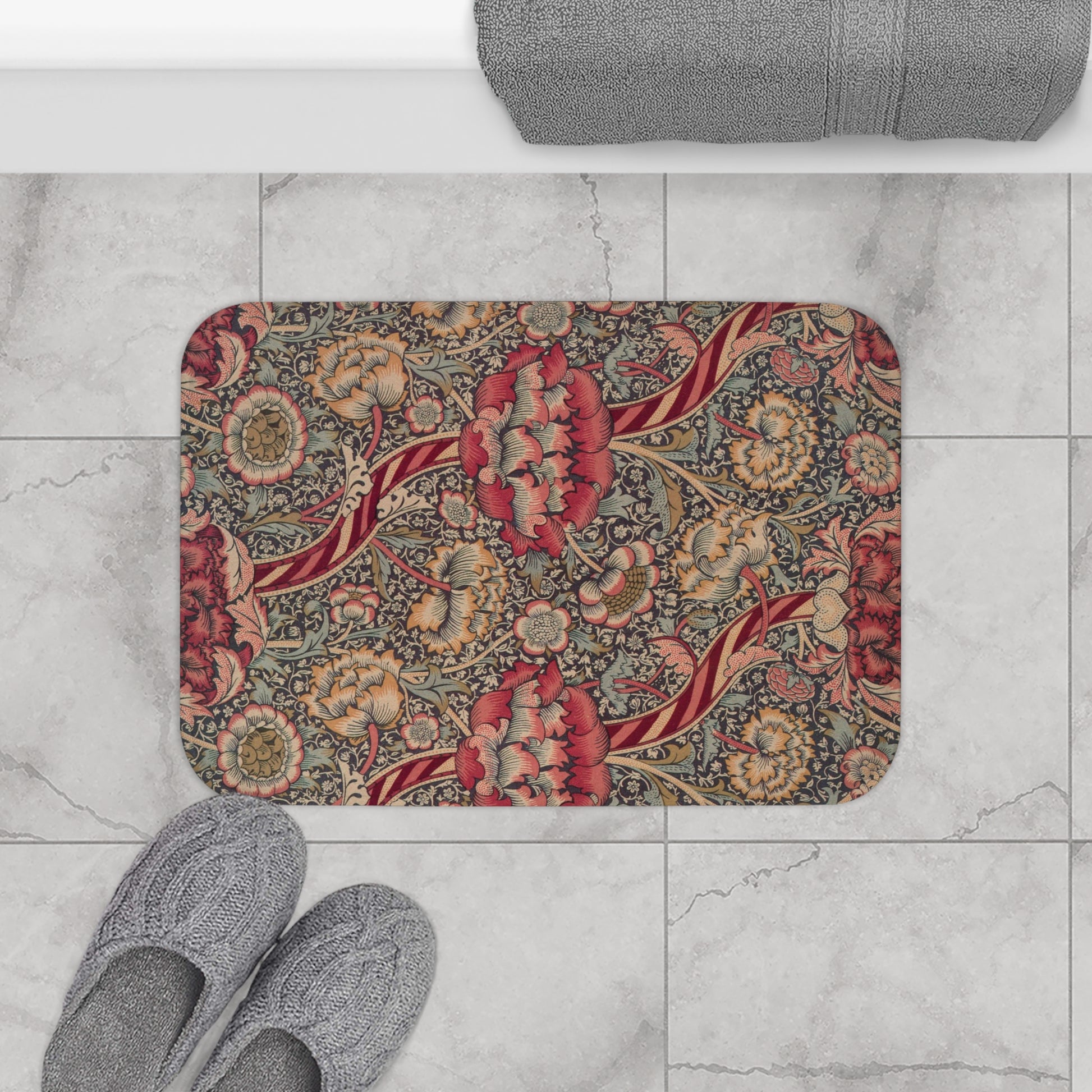 A rectangular microfibre bath mat with a floral pattern inspired by William Morris, predominantly red with a non-slip black border.
