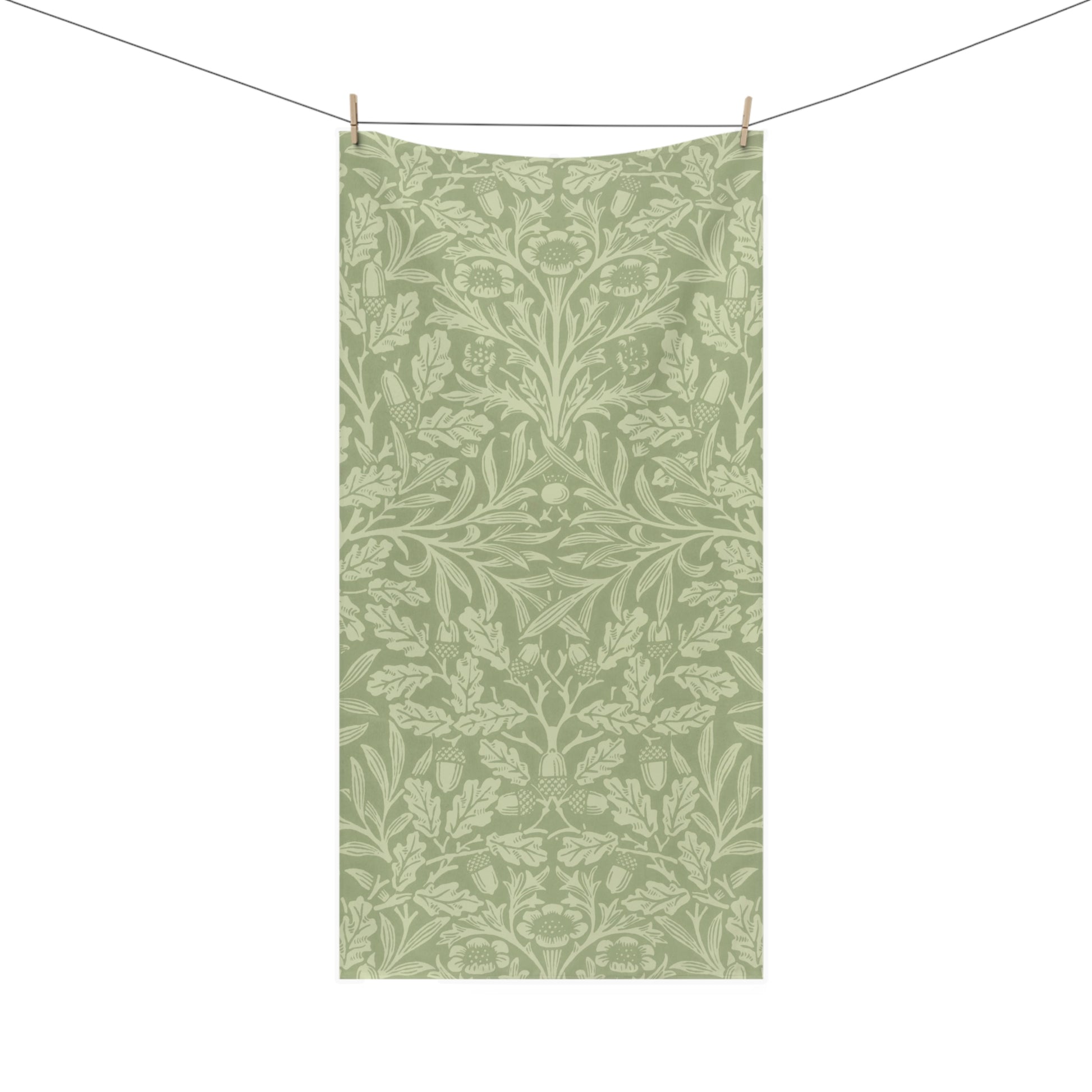 A rectangular fabric towel with an all-over botanical damask pattern in sage green and light sage green, hanging from a clothesline with two wooden clips against a plain white background.