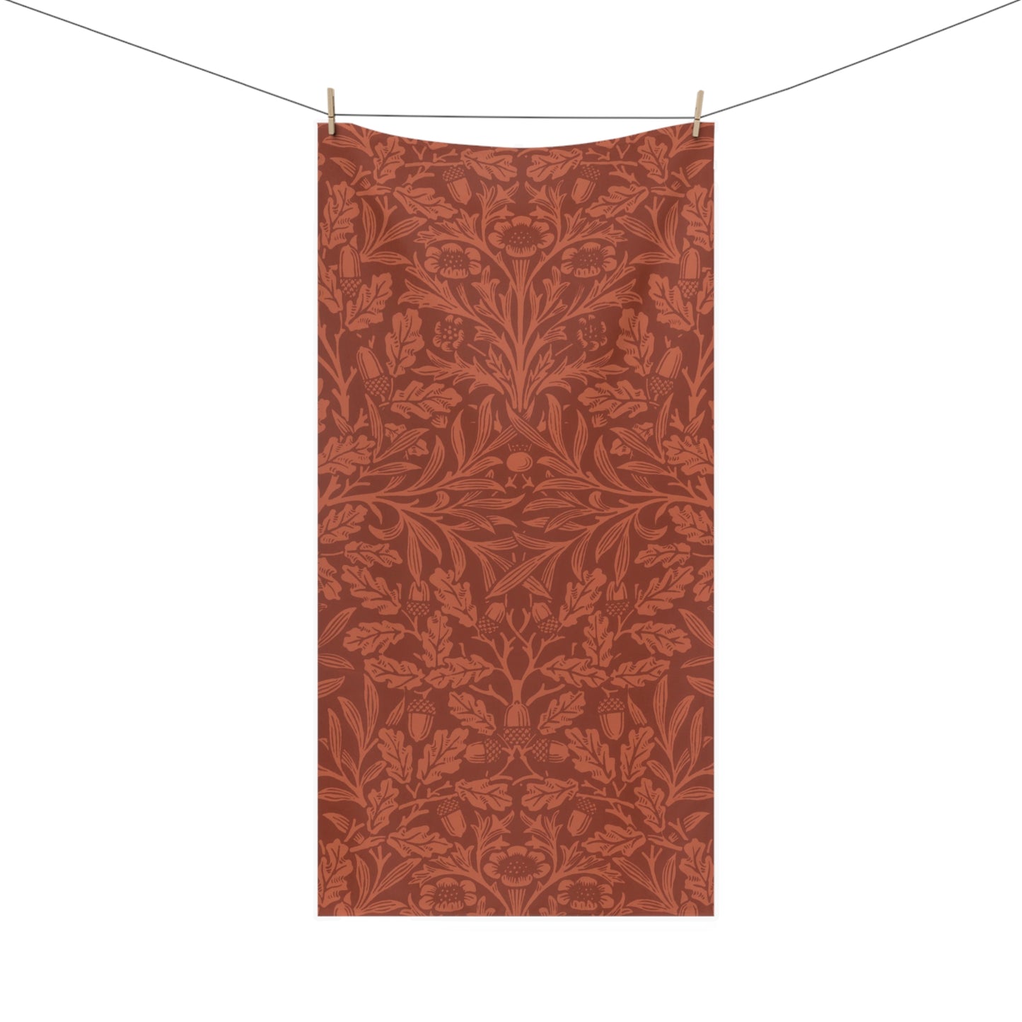 A rectangular textile hanging from a clothesline with two wooden clips, featuring an all-over botanical pattern in warm rust and terracotta tones on a white background.