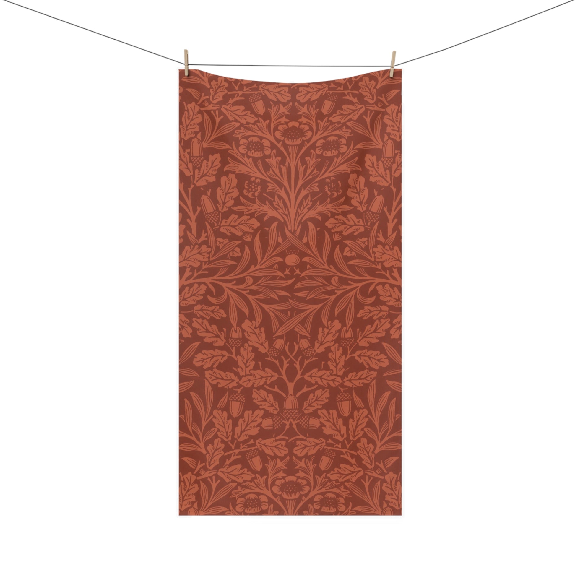 A rectangular textile hanging from a clothesline with two wooden clips, featuring an all-over botanical pattern in warm rust and terracotta tones on a white background.
