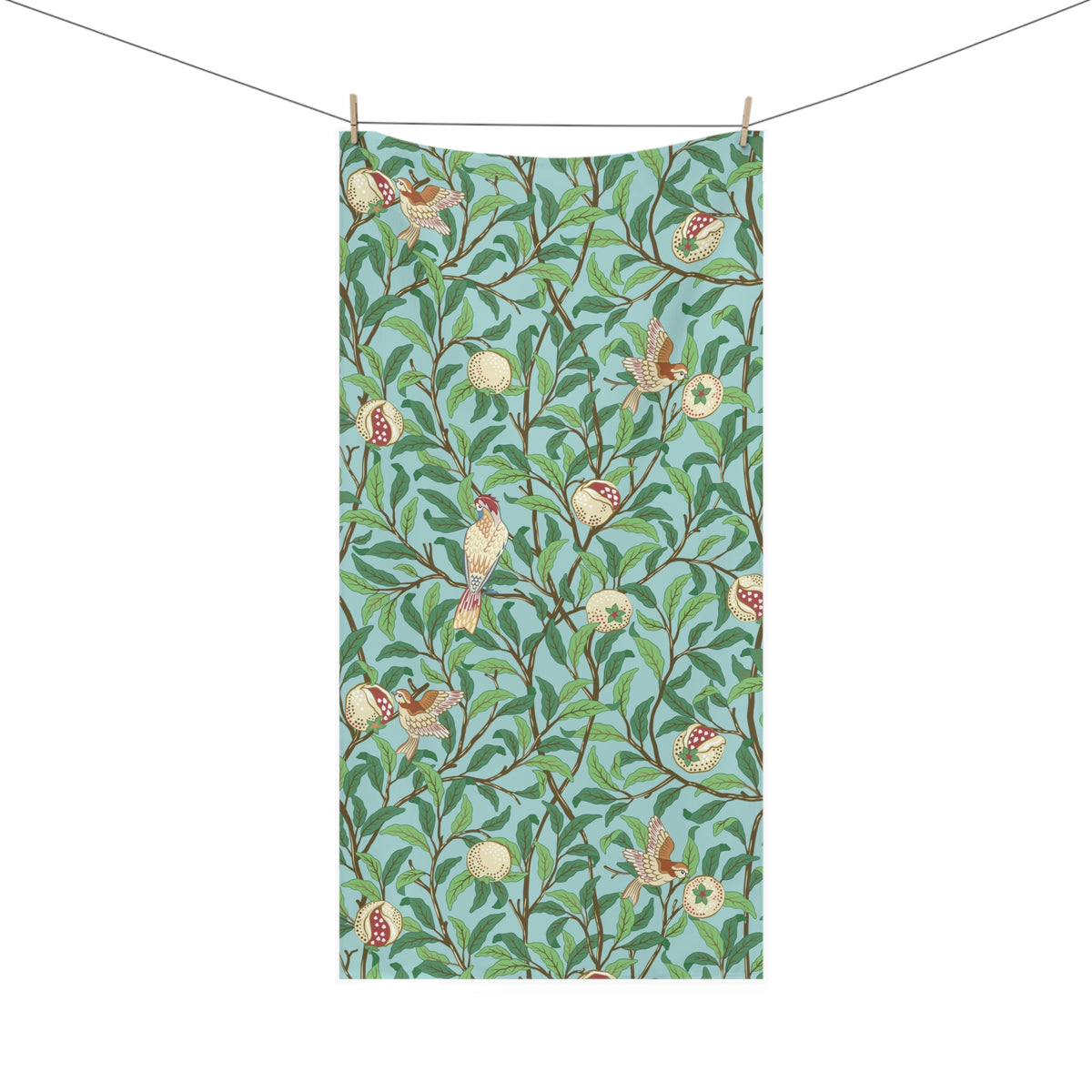 A rectangular bath towel with a repeating botanical and bird pattern, suspended from a string with wooden clips against a plain white background.