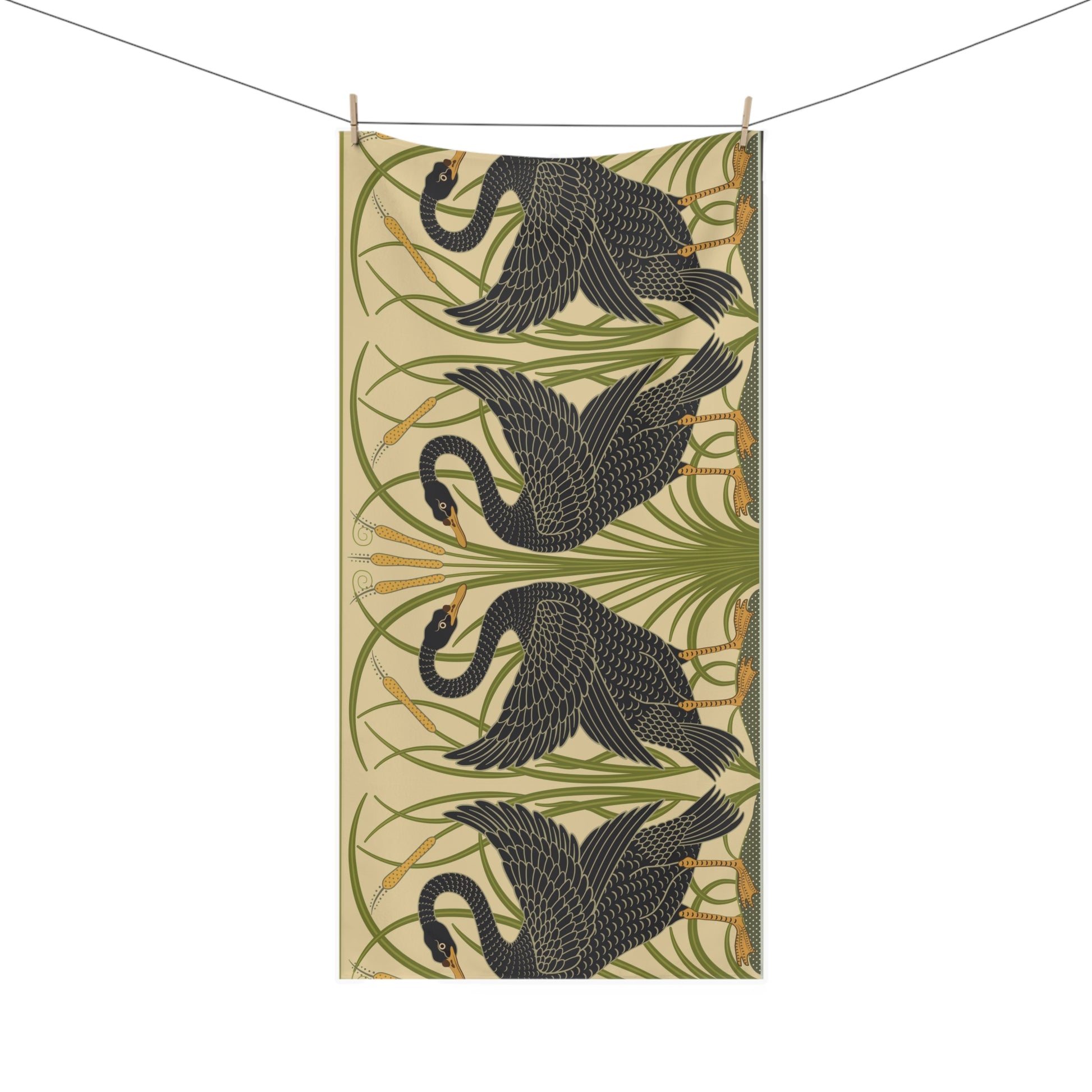 A vertical fabric panel or tapestry featuring a repeating pattern of four black swans with green reeds on a warm beige background, suspended by a string with wooden clips against a white background.