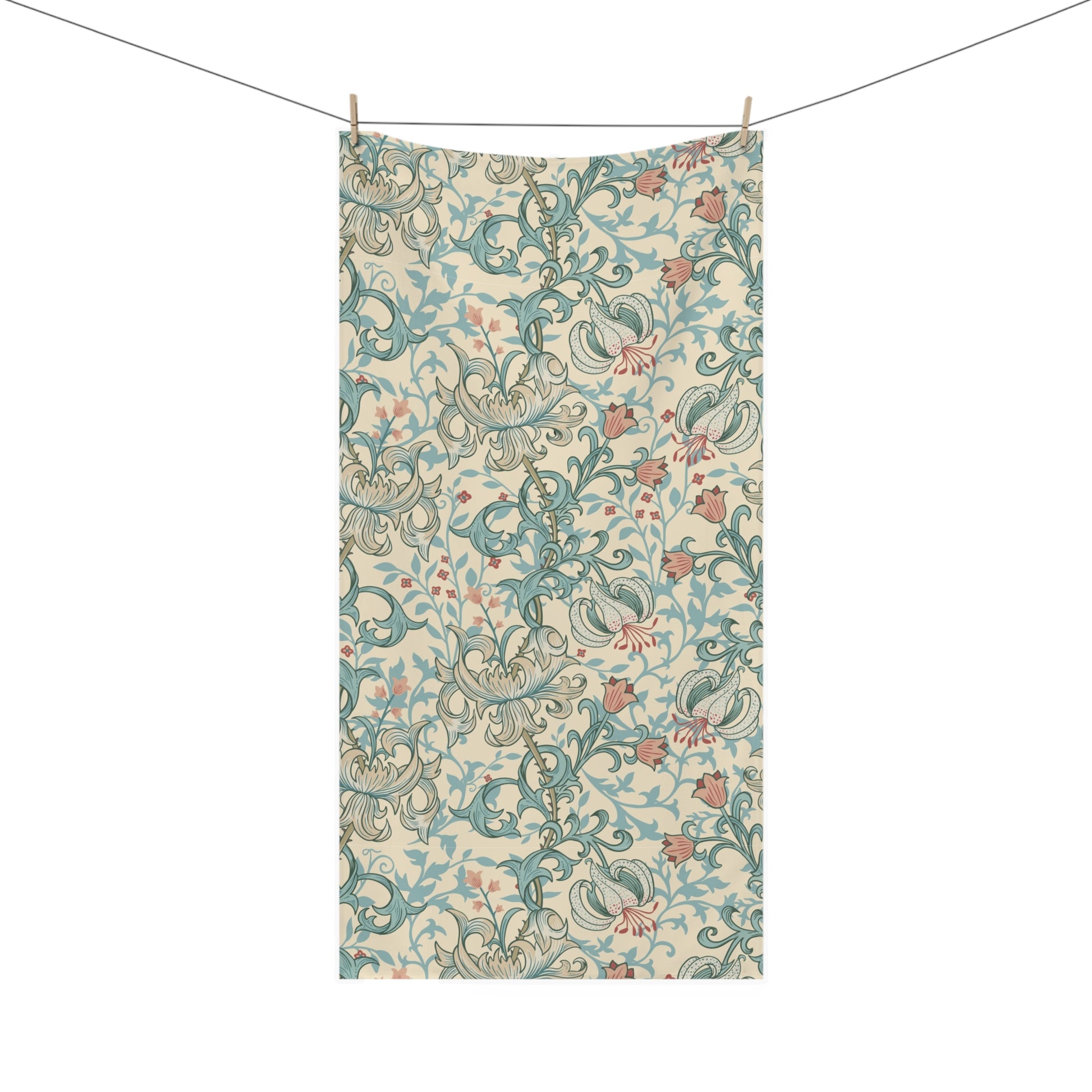 A rectangular fabric towel or scarf with an intricate floral and scroll pattern in teal, dusty pink, and olive green on a cream background, hanging from a clothesline with two wooden clips against a solid white background.
