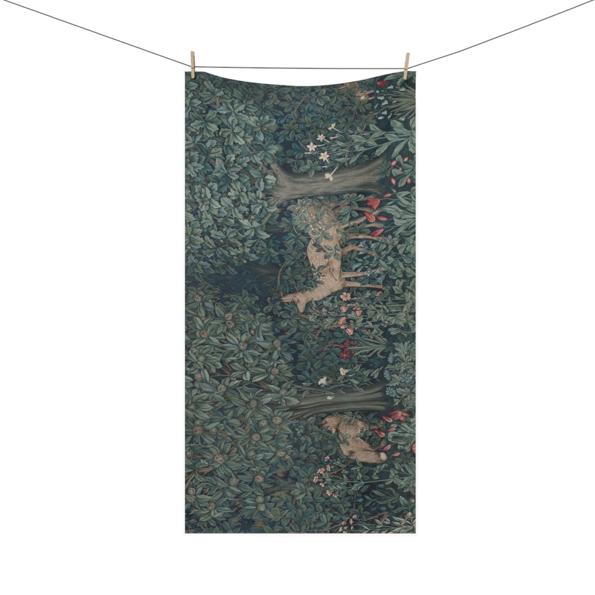 A rectangular bath towel featuring a detailed forest scene with dense green foliage, tree trunks, and small red and white flowers, hanging from a clothesline with wooden clips against a plain white background.