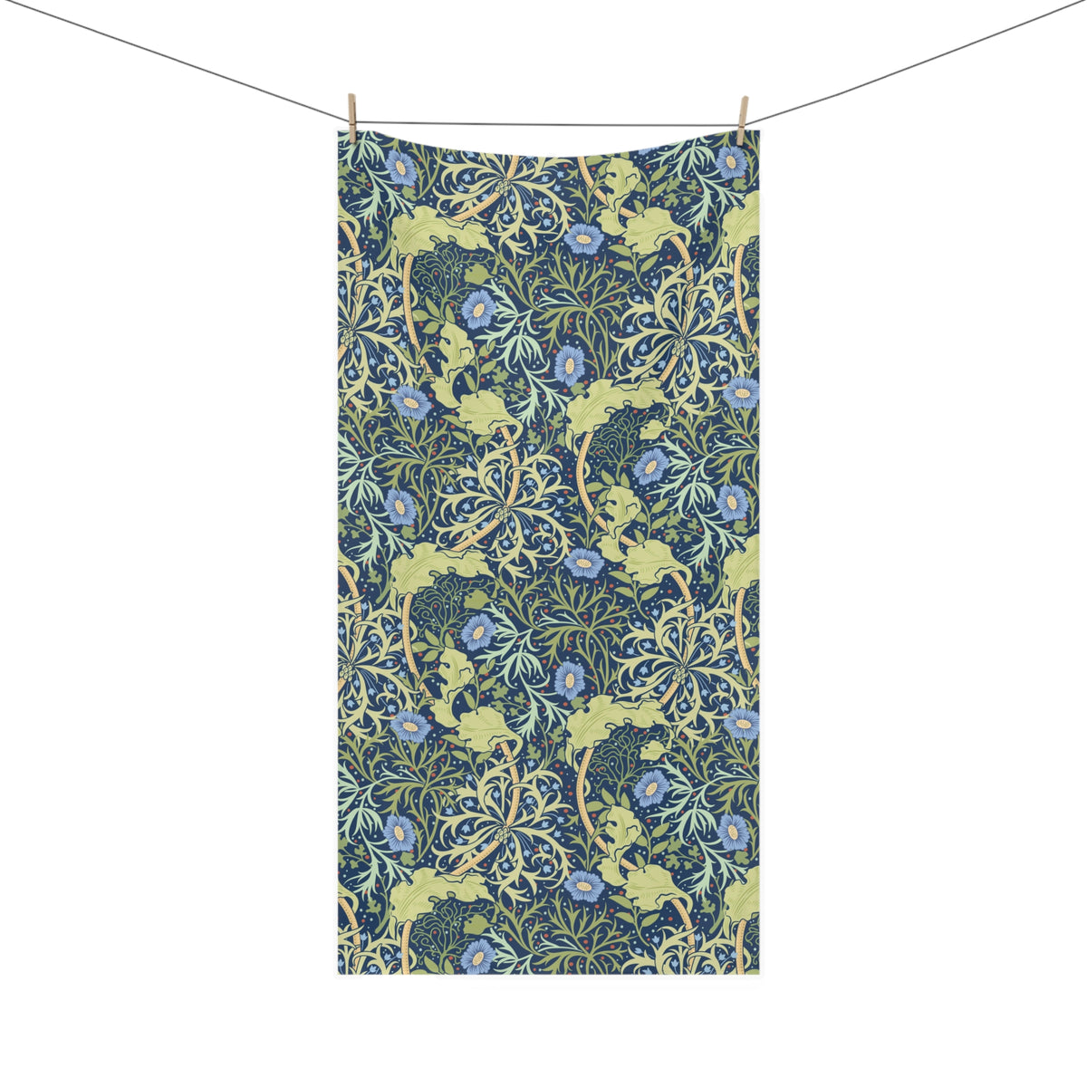 A rectangular bath towel, featuring a dense botanical pattern with blue flowers, green leaves, and yellow vines on a dark navy background. It is shown hanging from a clothesline with two wooden clips against a plain white background.