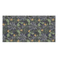 A rectangular textile or fabric sample with a dense botanical pattern featuring green leaves, gray floral motifs, and small yellow flower accents on a dark background, shown against a plain white backdrop.
