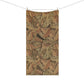 A rectangular fabric towel or blanket with a vintage-style botanical leaf pattern in warm brown, tan, and olive tones, hanging from two wooden clips on a clothesline against a plain white background.