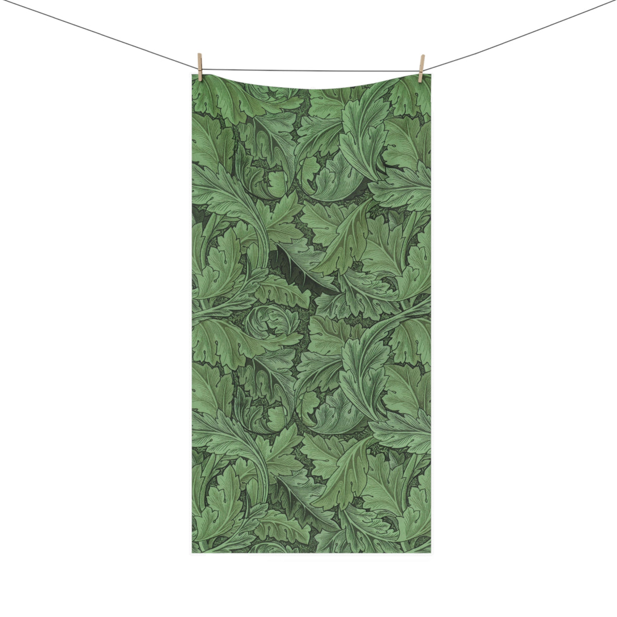 A rectangular beach towel with a green and dark green acanthus leaf pattern, hanging from a clothesline with two wooden clips against a solid white background.