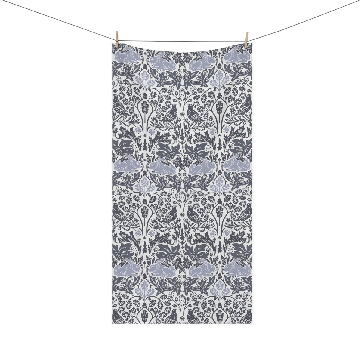 A rectangular towel with a classic William Morris-style floral damask pattern in gray, white, and muted blue-gray, hanging from a clothesline with two wooden clips against a plain white background.