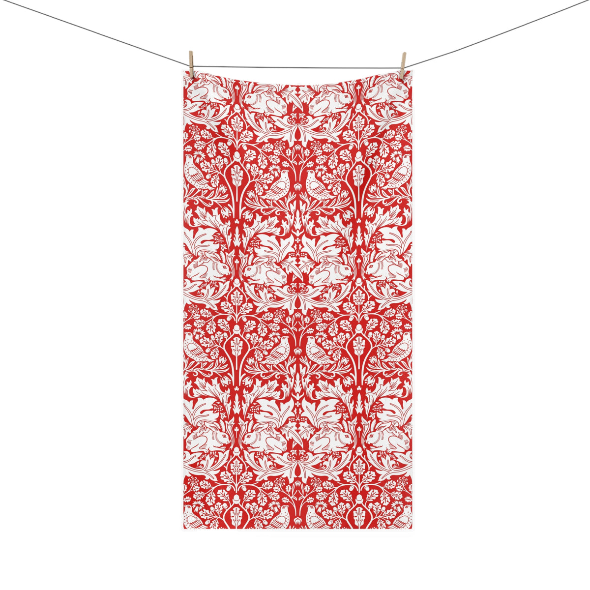 A rectangular fabric towel with a red and white ornate damask pattern, hanging from two wooden clothespins on a thin horizontal line against a plain white background.