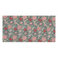 A rectangular towel featuring a dense floral and botanical pattern in pink, coral, cream, and muted blue on a white background.