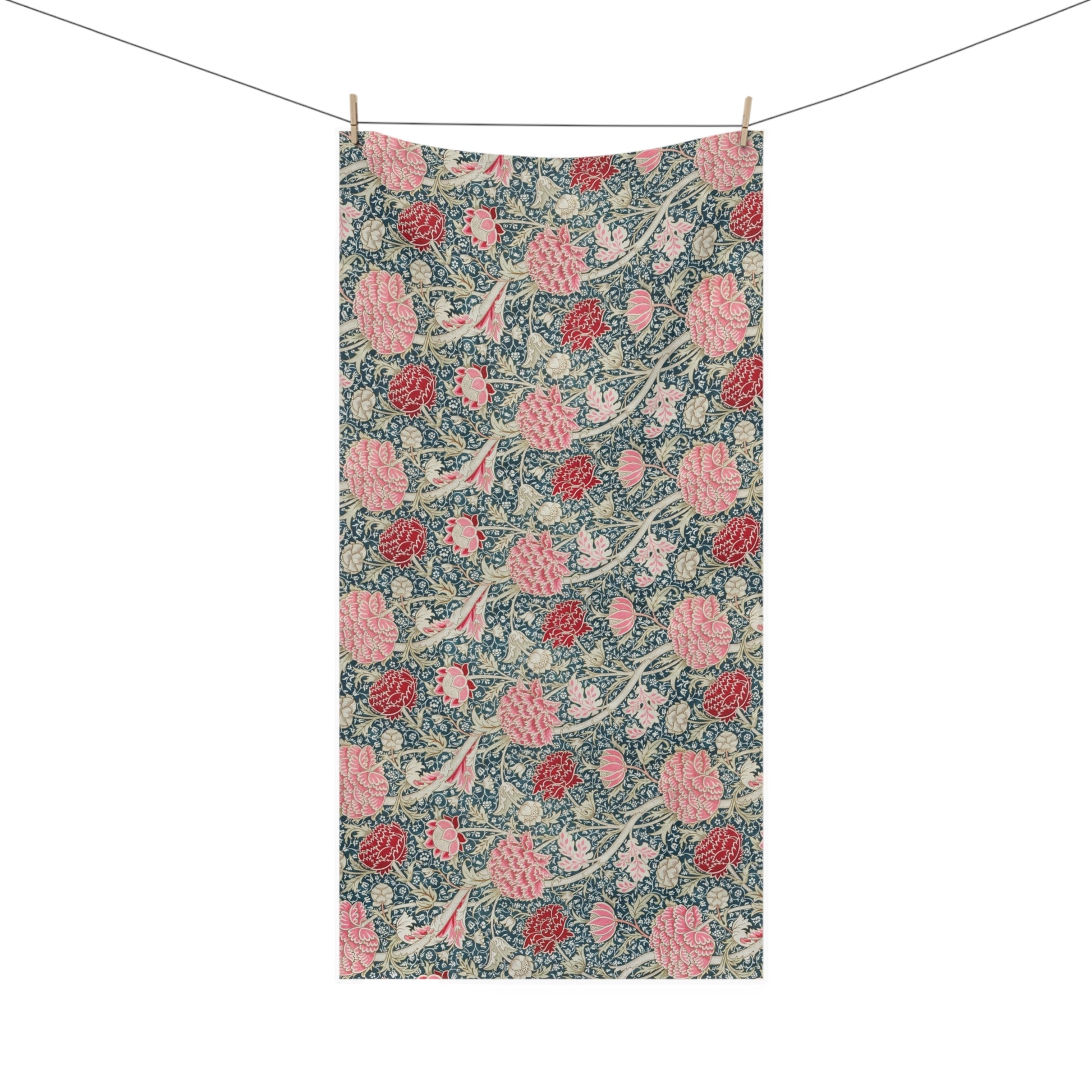 A rectangular fabric towel with a vintage floral pattern, hanging from two wooden clothespins on a string against a plain white background.
