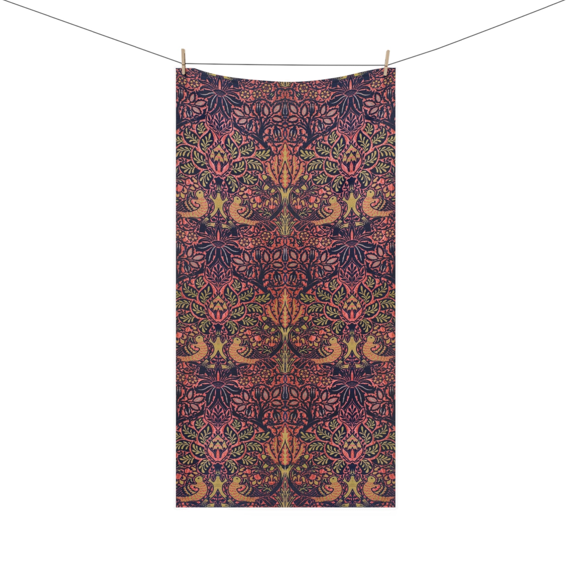 A rectangular textile with an intricate botanical and bird pattern in dark navy, pink, and olive green, hanging from a clothesline with two wooden clips against a plain white background.