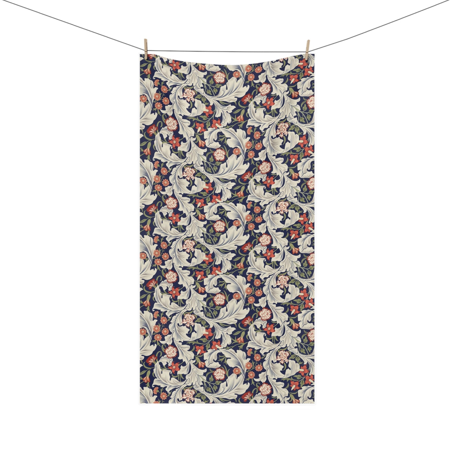 A rectangular bath towel with an all-over floral and botanical pattern hangs from a clothesline with two wooden clips against a plain white background.