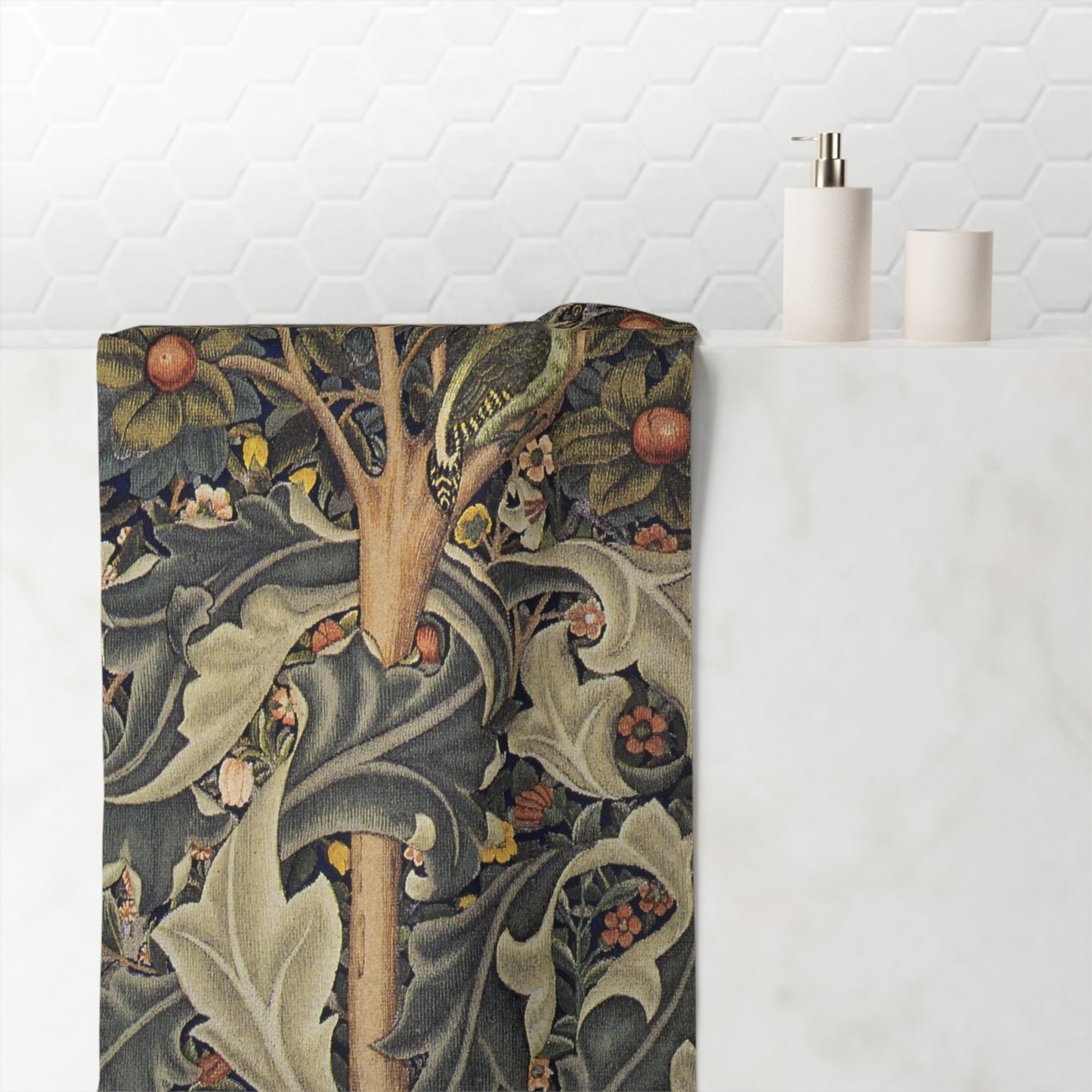 A bath towel with a detailed William Morris-style botanical pattern featuring a bird, leaves, and berries, draped over a white marble bathroom counter next to minimalist white bath accessories.