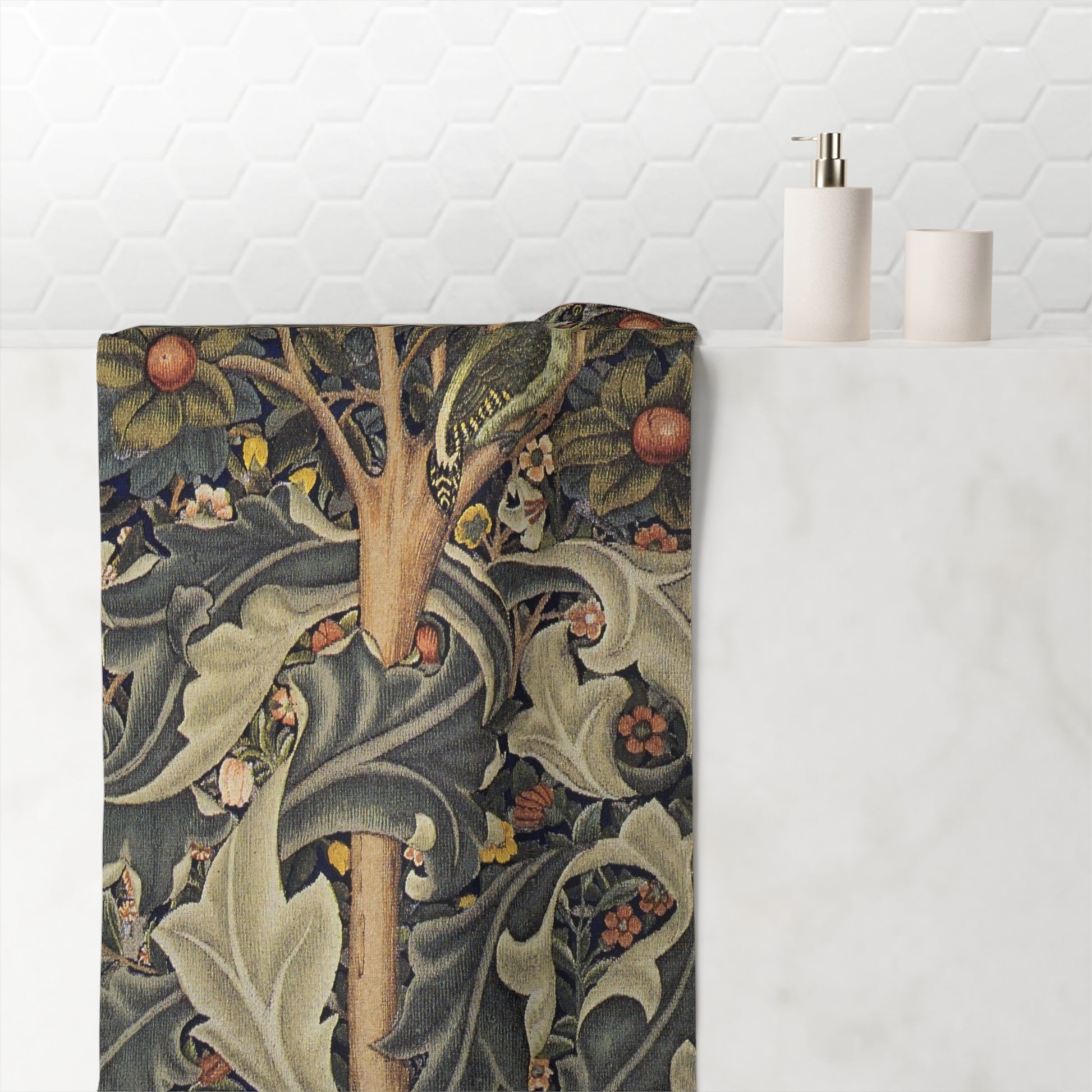 A bath towel with a detailed William Morris-style botanical pattern featuring a bird, leaves, and berries, draped over a white marble bathroom counter next to minimalist white bath accessories.