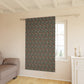 Floral patterned curtain hanging in a room with a sofa and window.