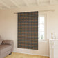 Patterned curtain hanging in a room with a sofa and window.