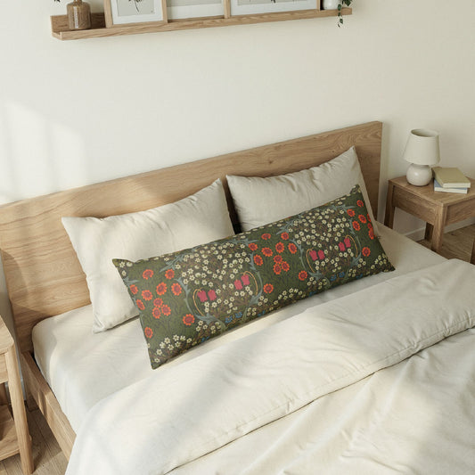 A rectangular lumbar pillow with a green floral pattern rests on a bed with white bedding and two white pillows in a minimalist bedroom setting.