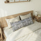 Bed with decorative pillows and a wooden headboard in a bedroom setting.