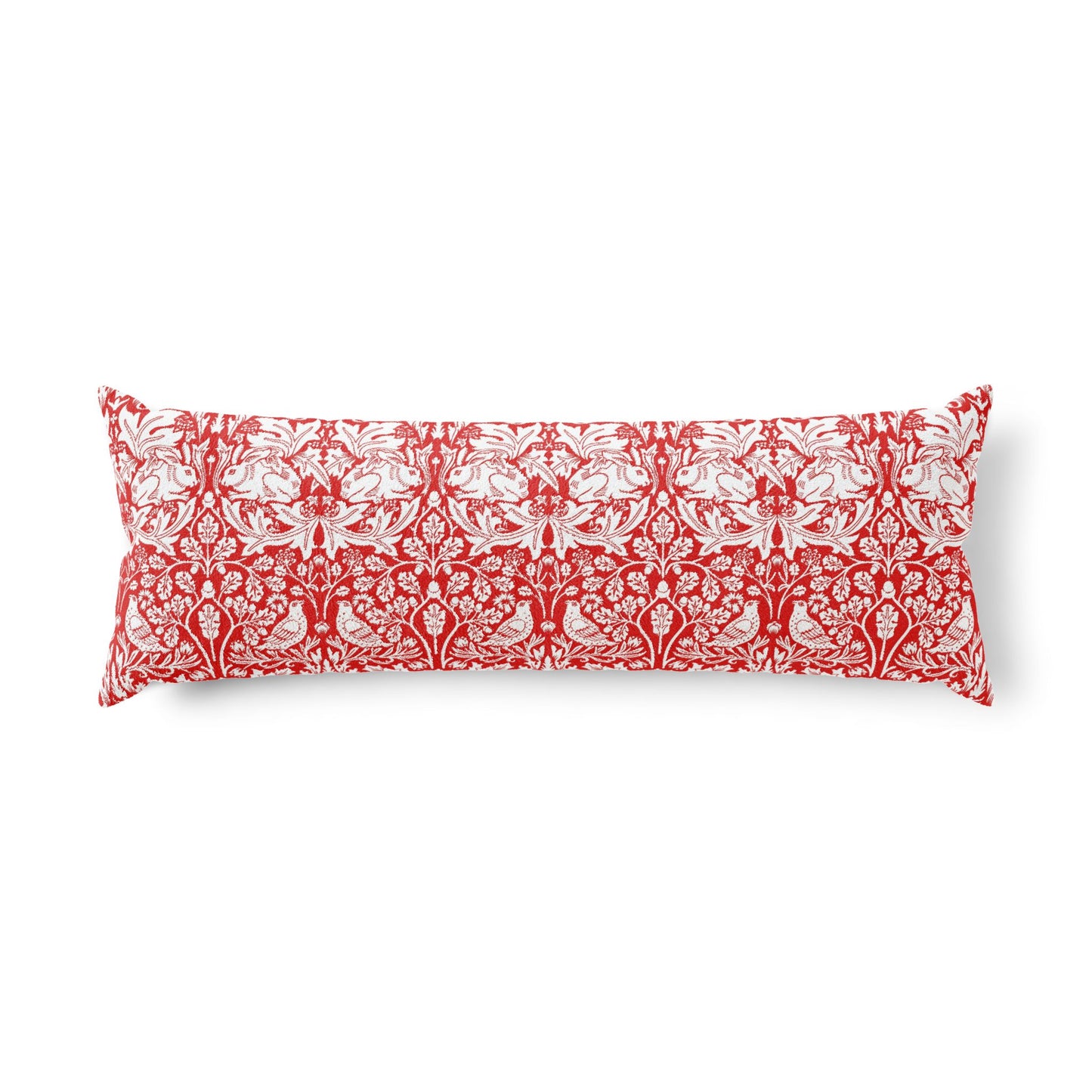 Bed with wooden headboard and decorative pillows, including a red floral pillow in a William Morris pattern called Brer Rabbit.