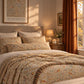 A beautifully styled bed in a warm, sunlit bedroom featuring a William Morris style floral and bird patterned duvet cover and matching pillow shams. The room has warm orange curtains, a bedside table with a lamp and candle, and a framed William Morris print on the wall.